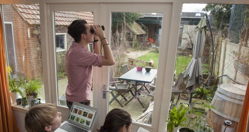 Drie jongeren tellen vanuit hun kamer de vogels in de tuin voor de Nationale Tuinvogeltelling.