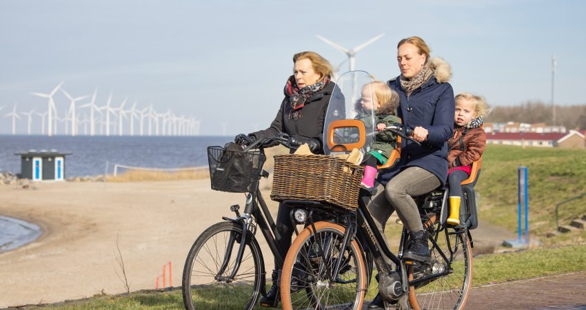 Fietsers langs het IJsselmeer met op de achtergrond windmolens